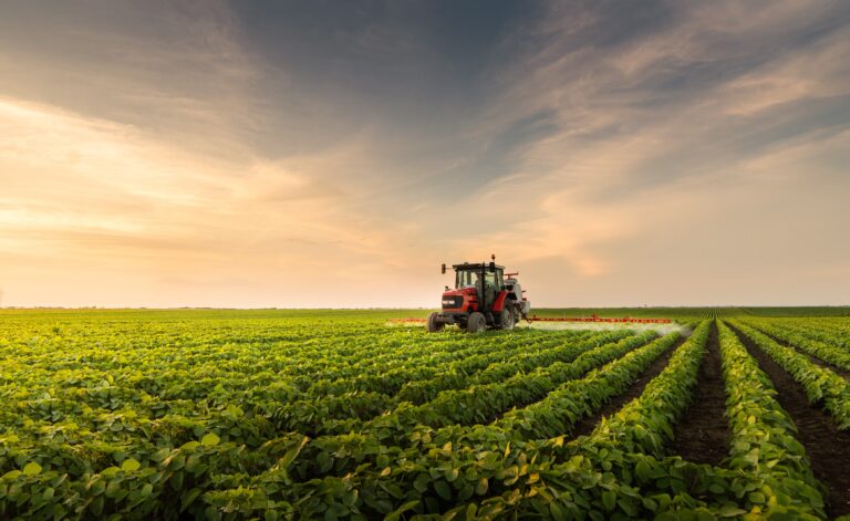 Tractor spraying pesticides at soy bean fields